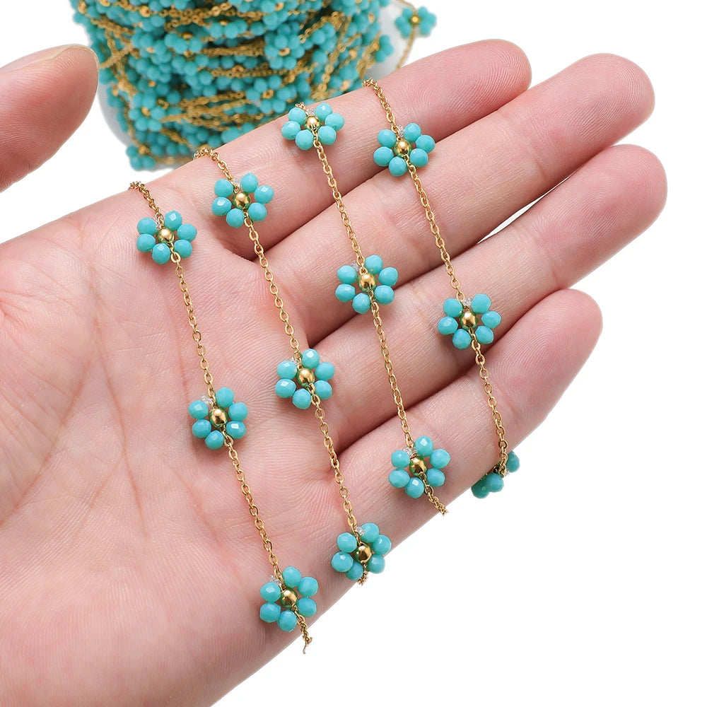 Turquoise daisy flower beaded chain with gold-tone links held in hand