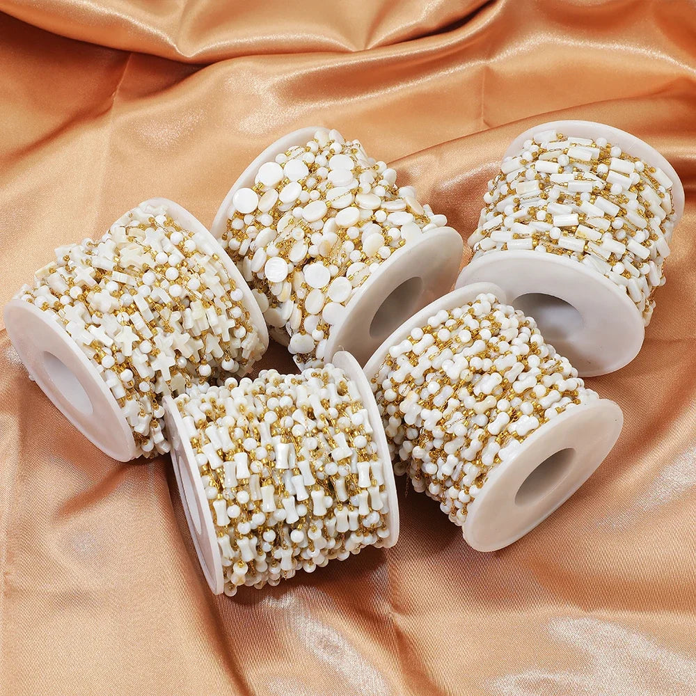 Multiple white-and-gold beaded chain spools with shell-style accents for jewelry making