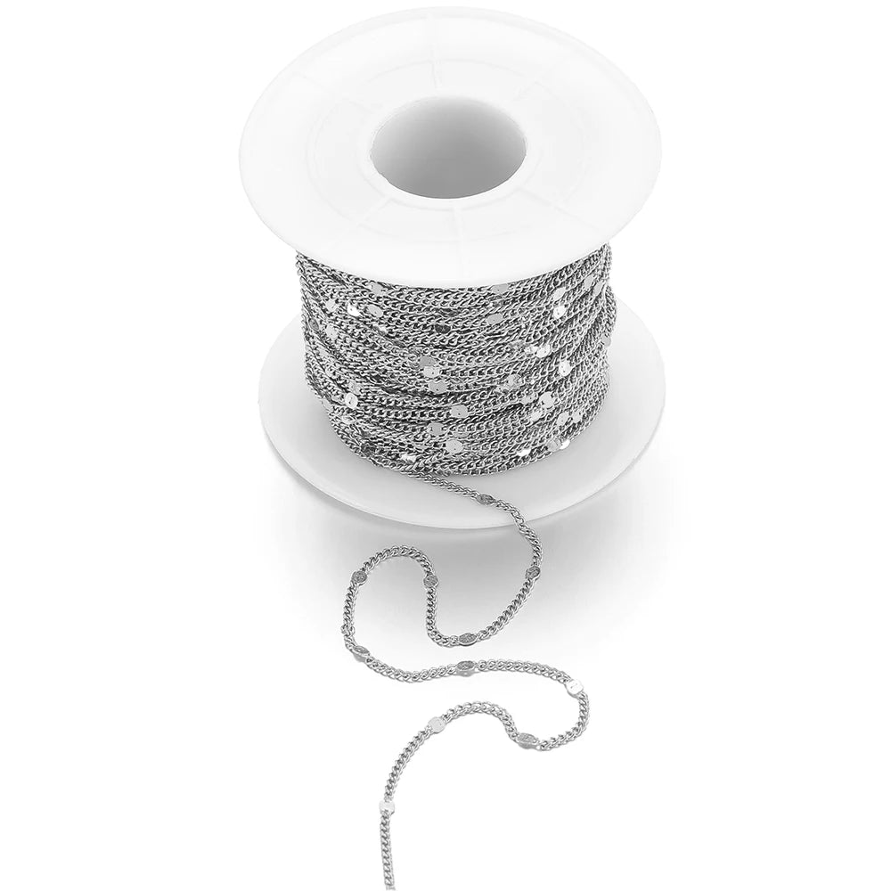 Silver textured flat oval chain on white spool with loose dangling links