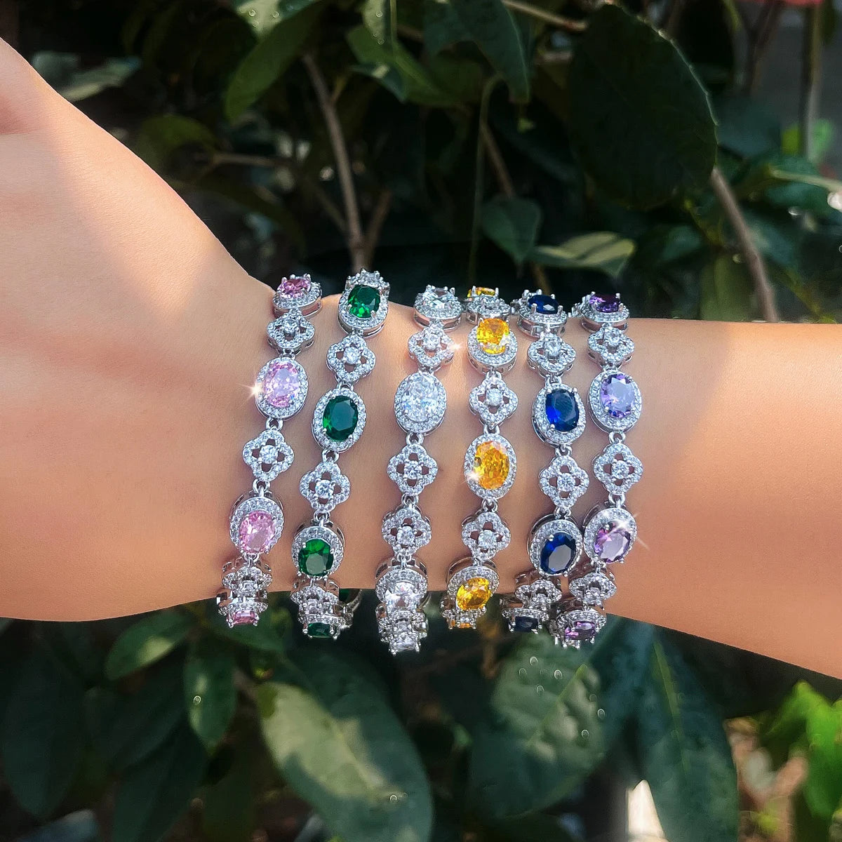 Colorful oval crystal flower tennis bracelets shown in several gemstone colors on a wrist