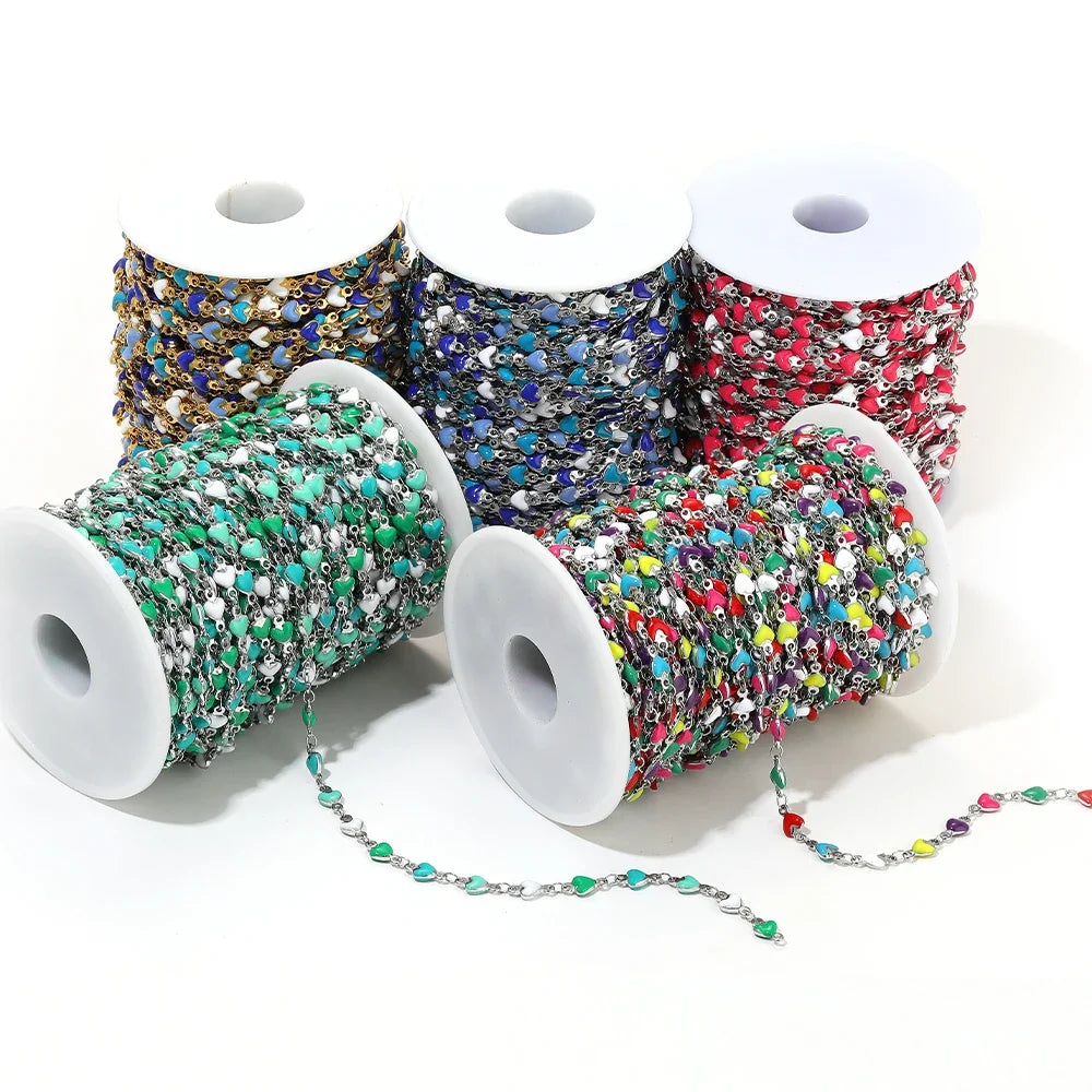 Colorful enamel heart link chains on white reels: blue, teal, red, gold, silver