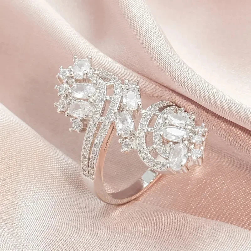 Rose-gold cubic zirconia ring with clear oval stones, curved halo bands, and prong settings