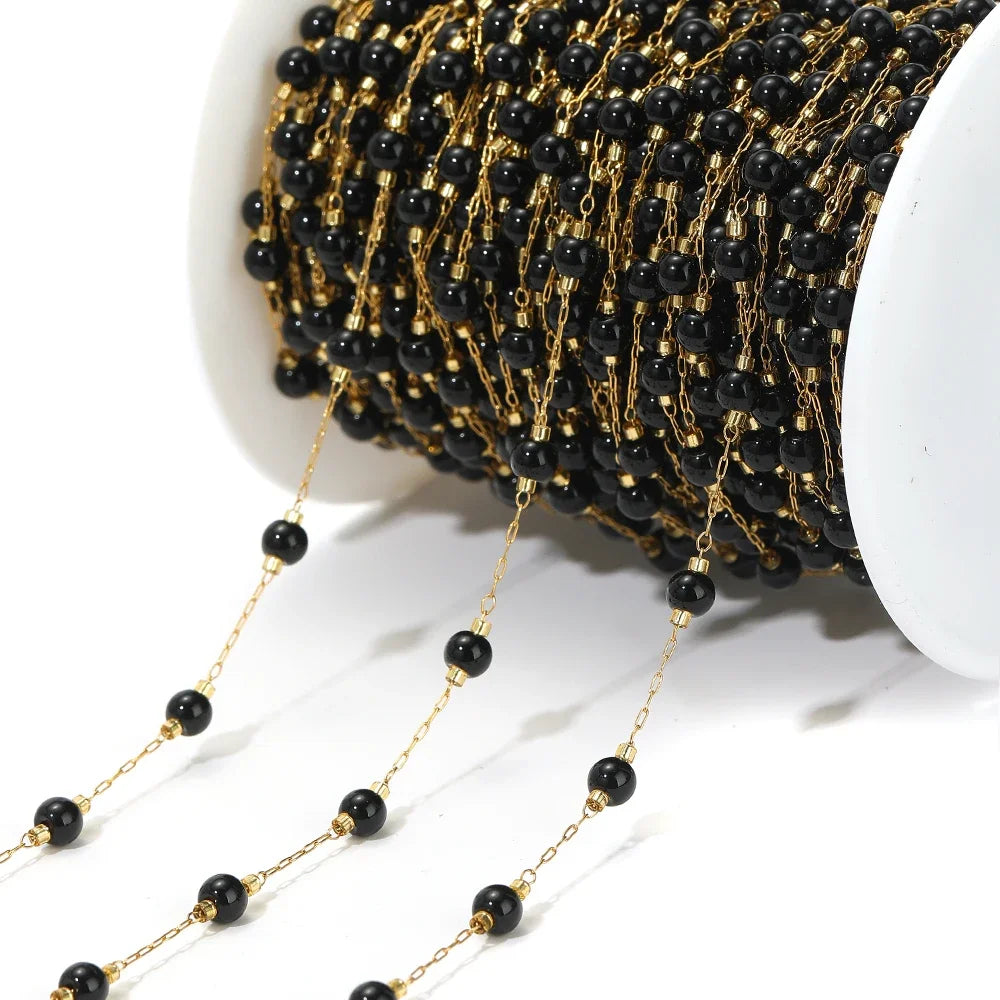 Black bead chain with gold-tone links and round black beads on a white spool