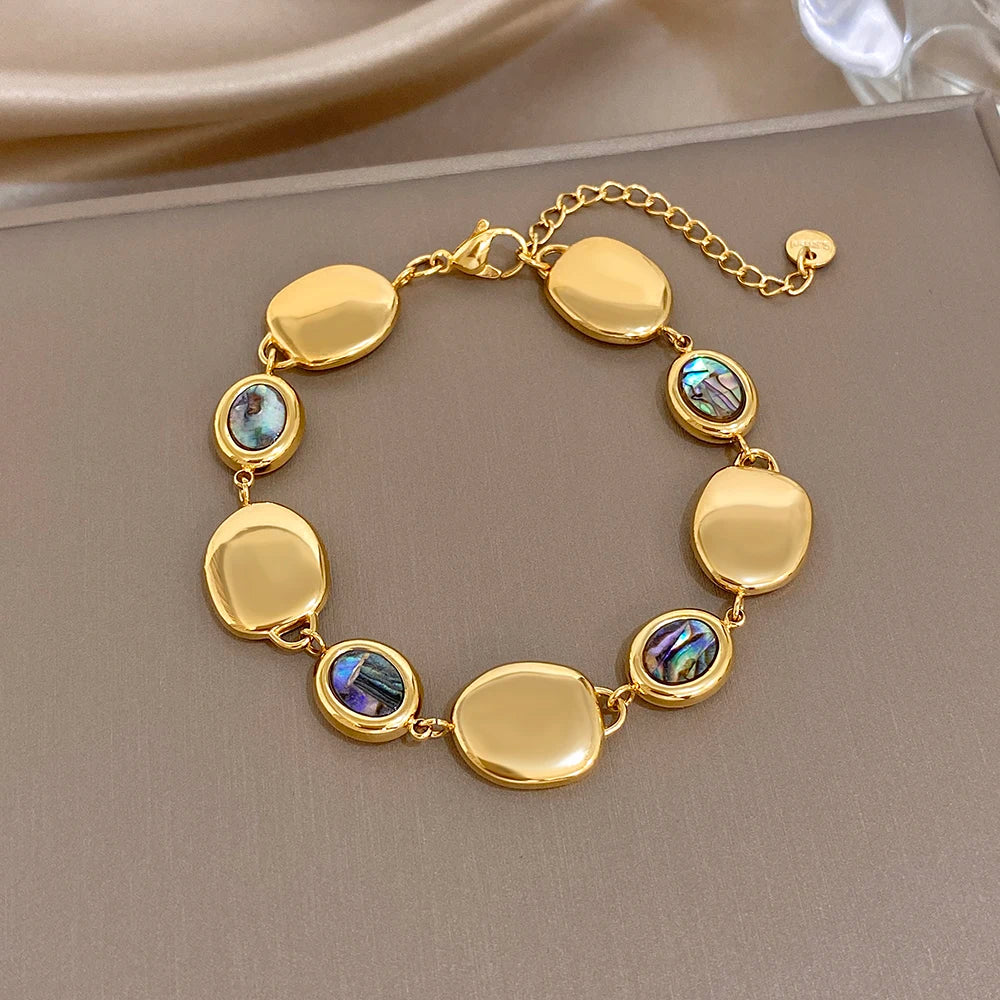 Gold-tone link bracelet with glossy oval discs and iridescent abalone shell inlays