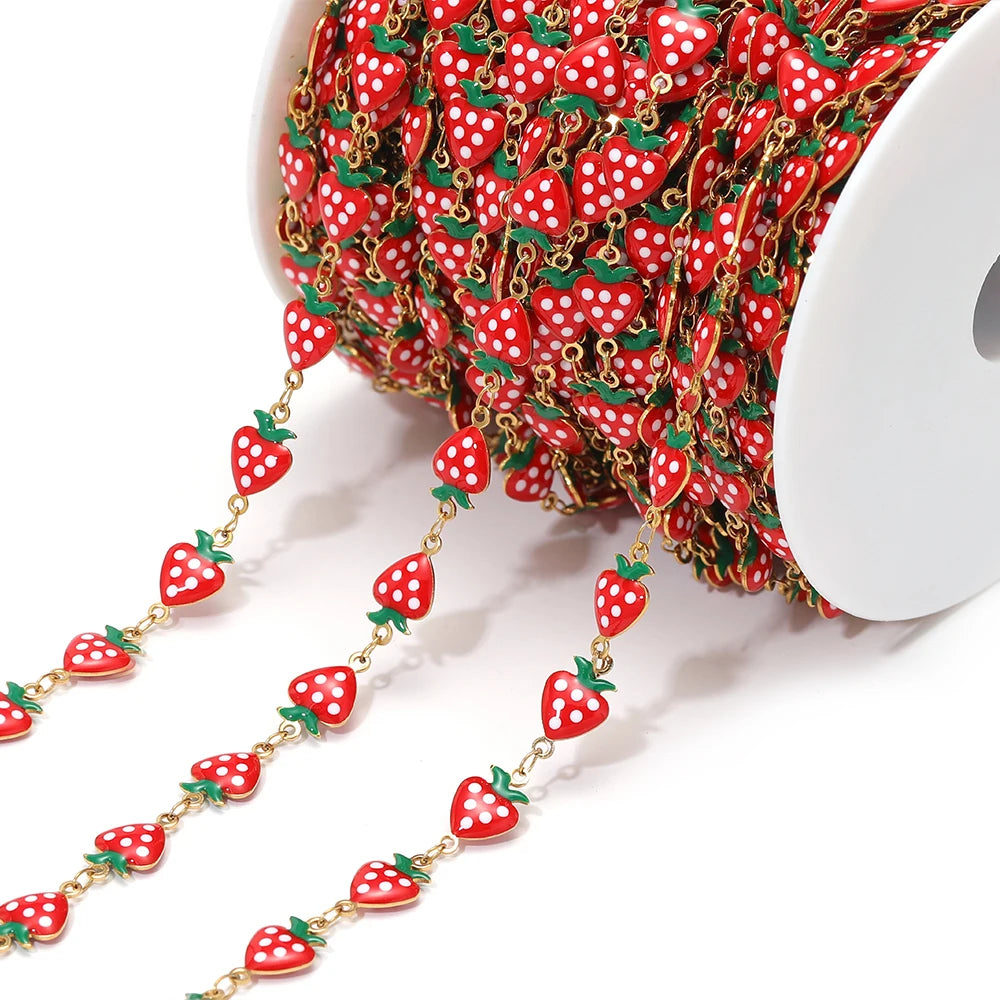 Red enamel strawberry charm chain with gold-tone links on a spool for DIY jewelry