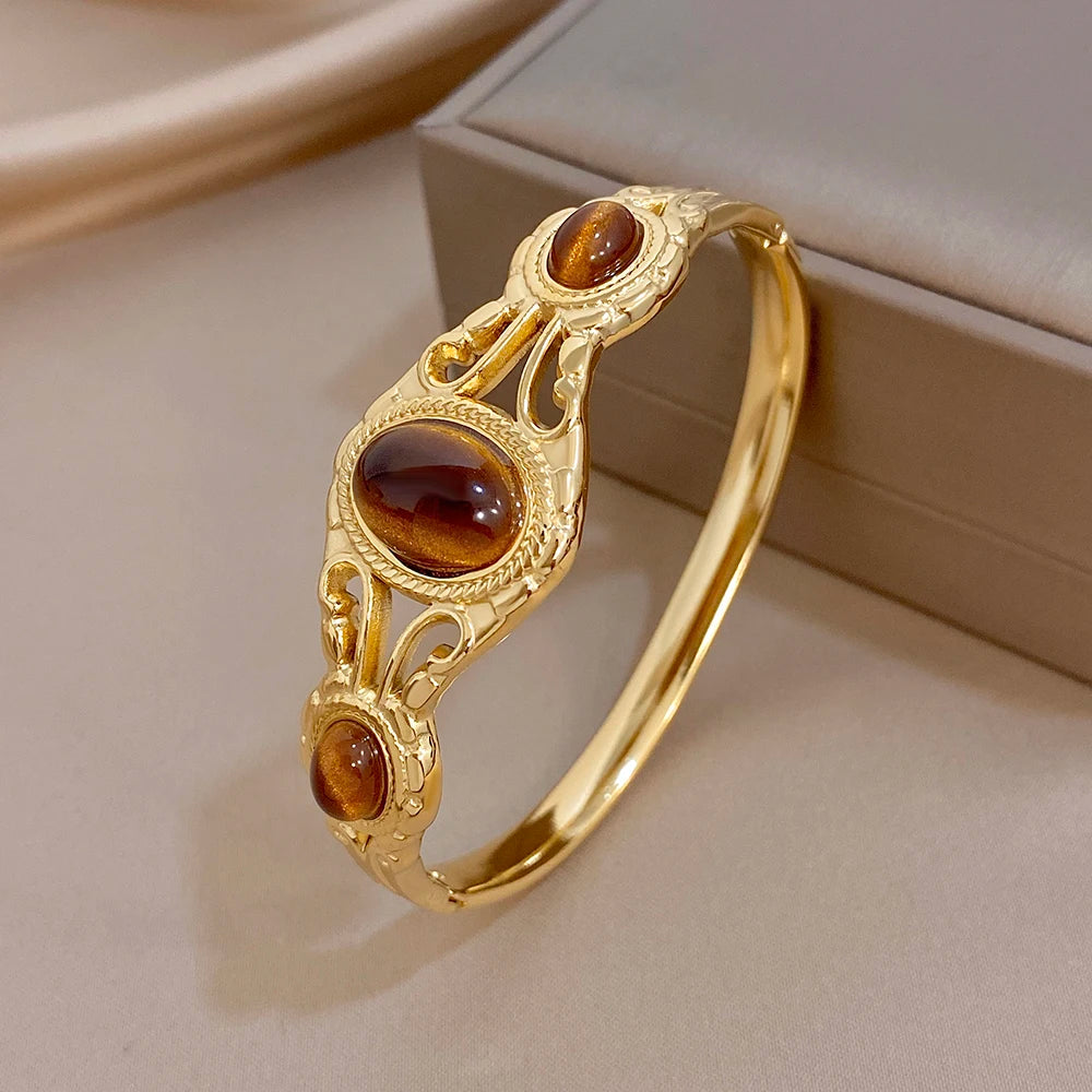 Gold-tone geometric cuff bangle with oval brown tiger-eye cabochons on open frame