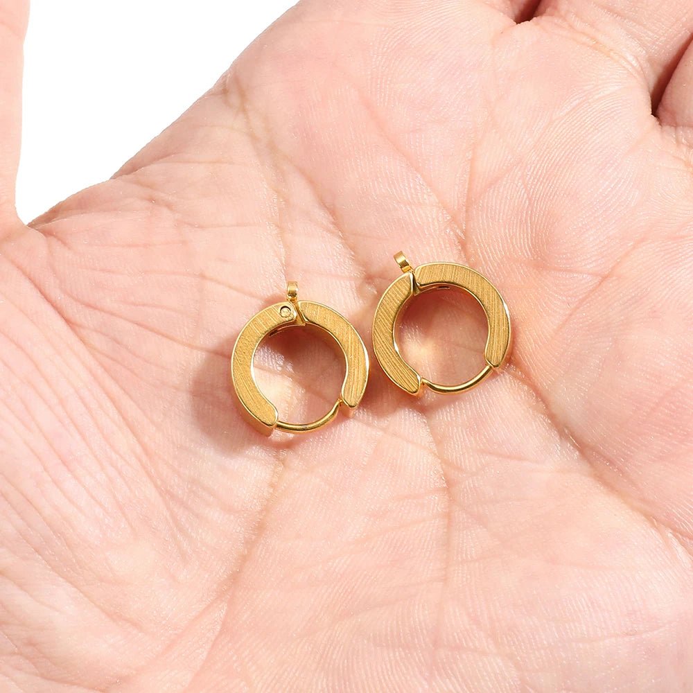 Gold huggie hoop earring hook clips held in hand, close-up