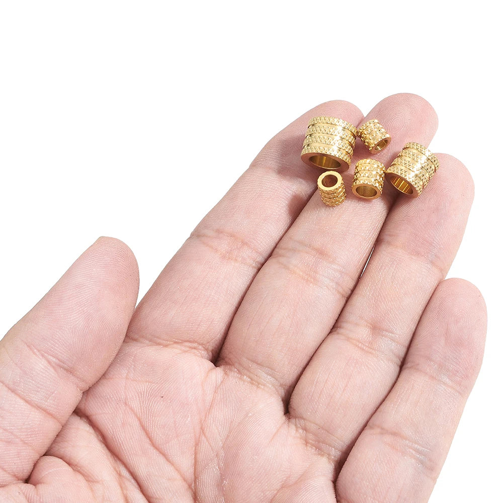 Gold-tone large-hole spacer beads held in hand, textured pattern with open center holes