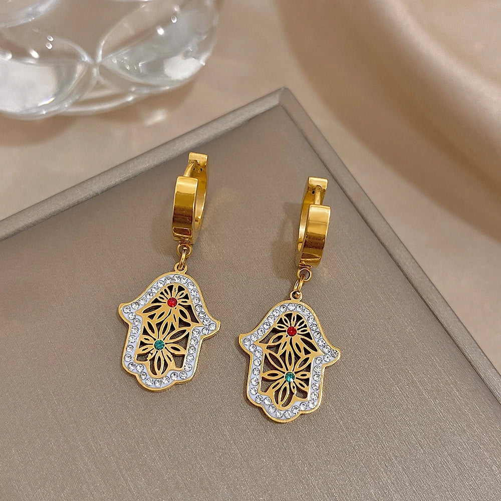 Pair of gold-tone hoop earrings with dangling crystal-edged hamsa filigree charms