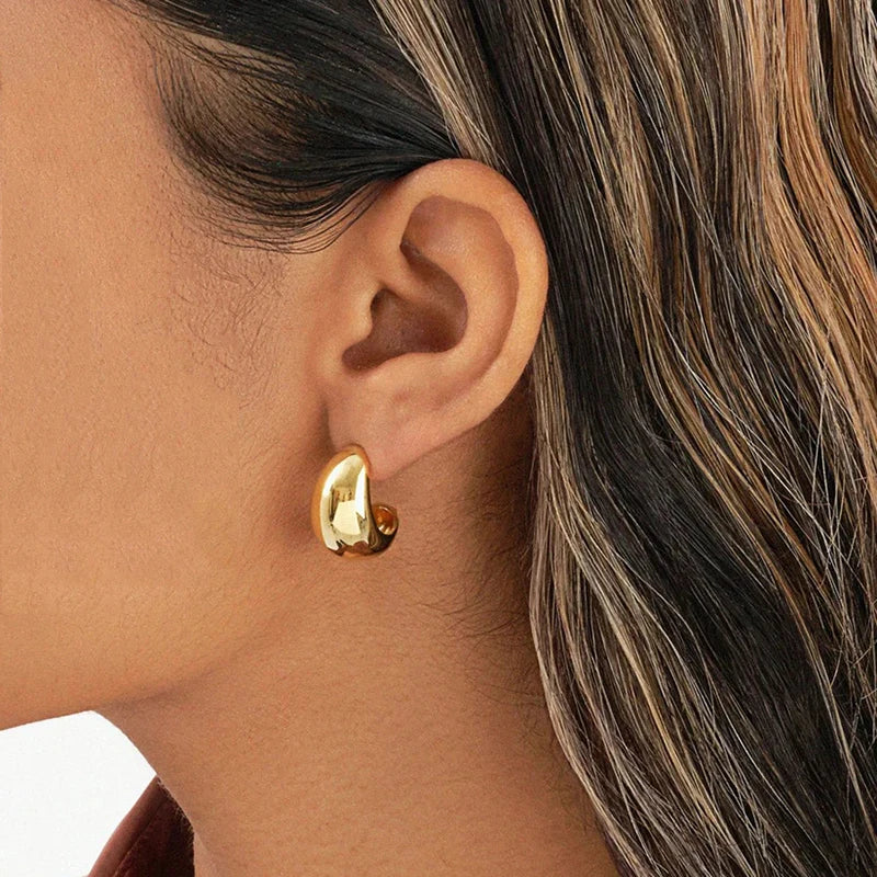 Gold-tone small dome hoop earring shown worn on an ear
