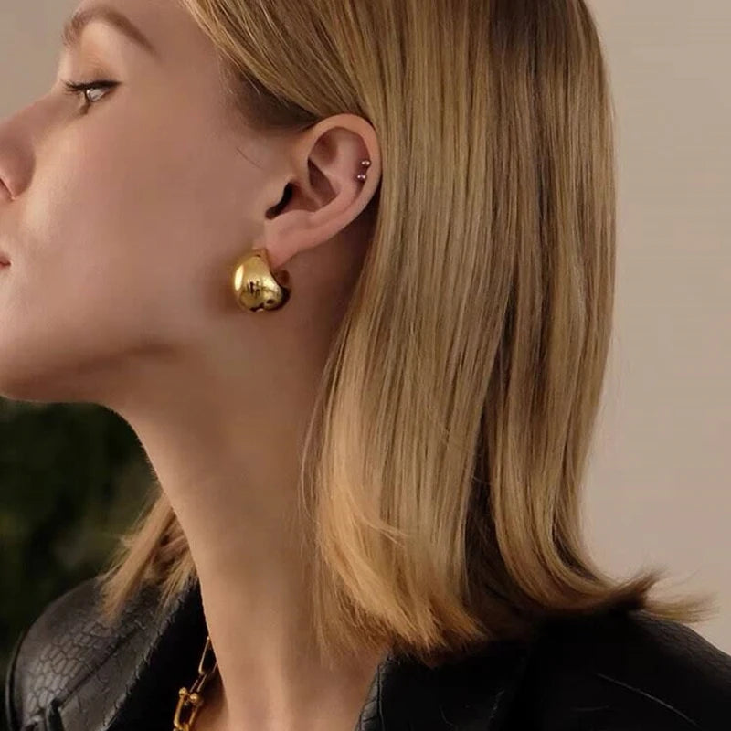 Gold-tone rounded dome hoop earring shown worn on an ear