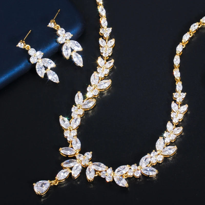 Gold cubic zirconia leaf-drop necklace with matching drop earrings, flat lay