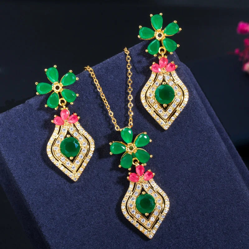 Gold-tone jewelry set with green flower details, pink accents, and crystal-edged drops