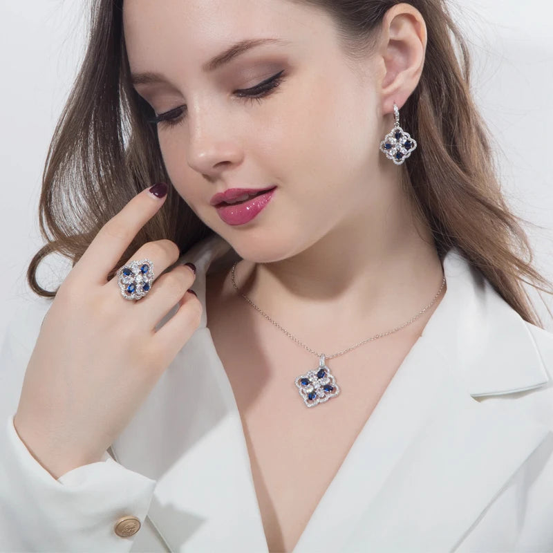 Model wearing blue-accented floral zircon pendant necklace, drop earring, and ring