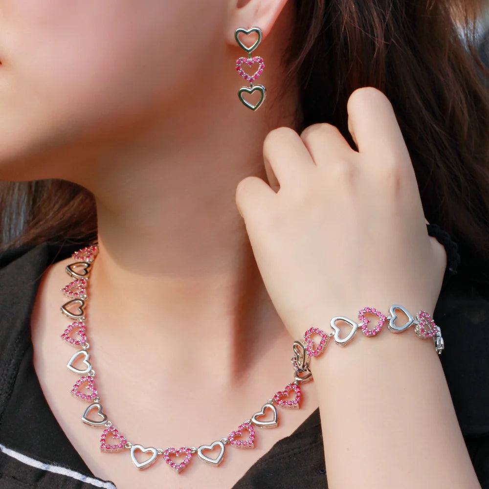 Pink and silver heart-link necklace, bracelet and dangling earrings modeled together