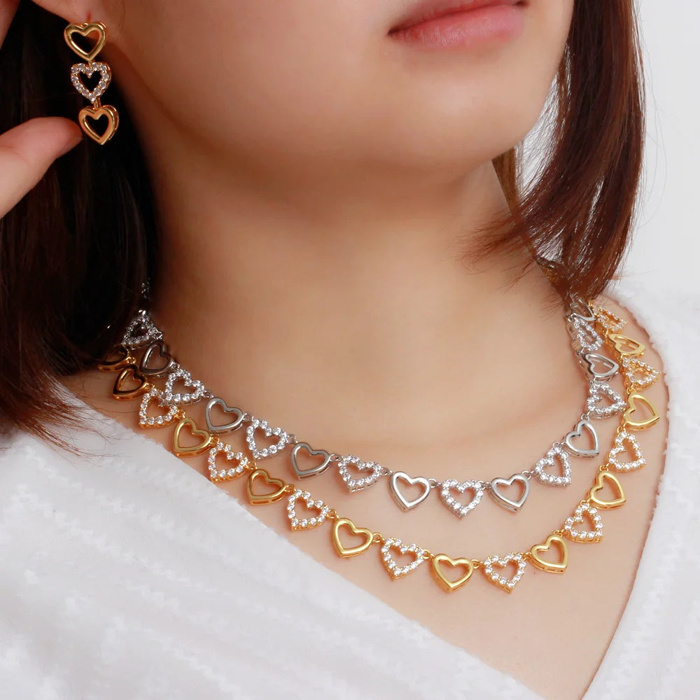 Gold and silver-tone heart necklace and dangling earring set with clear stones, modeled