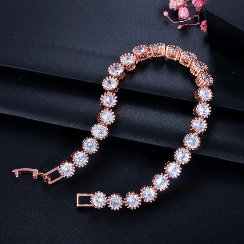 Rose gold-tone bracelet arranged open, showing round halo CZ stones and clasp