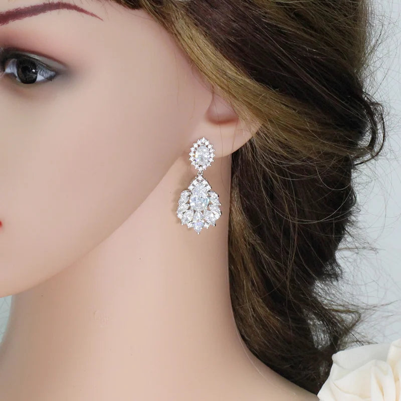 Silver-toned CZ drop earrings with oval halo studs, worn on the side of the ear