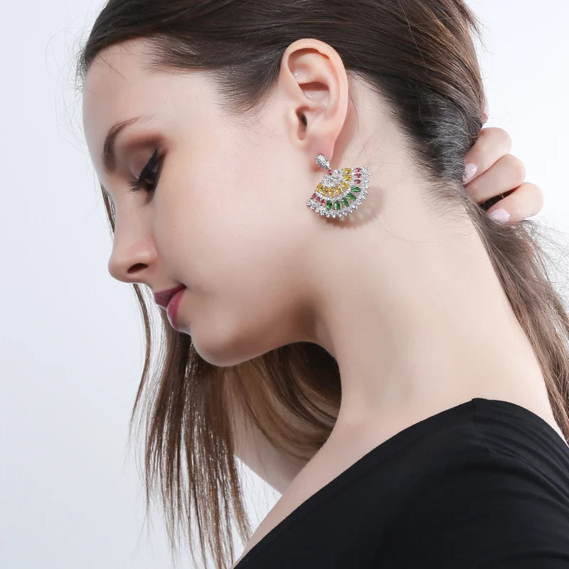 Close-up of a multicolor fan-shaped CZ drop earring worn on the ear