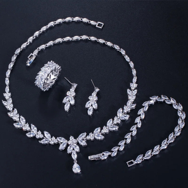 Silver-tone cubic zirconia four-piece jewelry set laid out: necklace, earrings, bracelet, ring