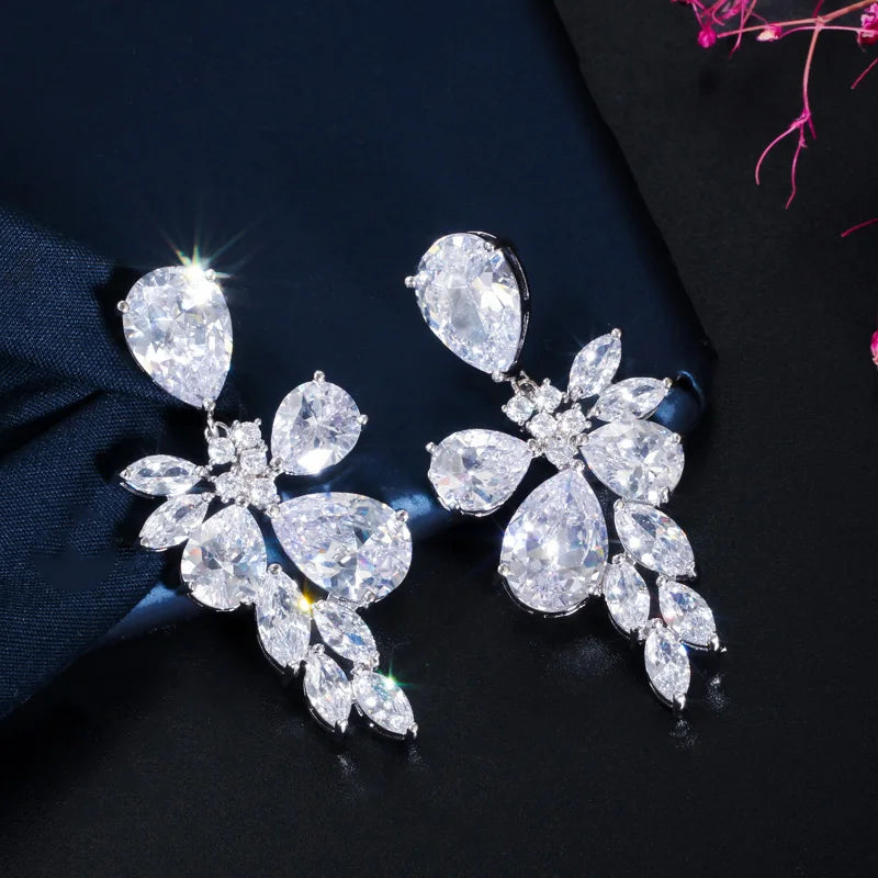 Angled view of long flower-shaped crystal drop earrings with pear-cut stones