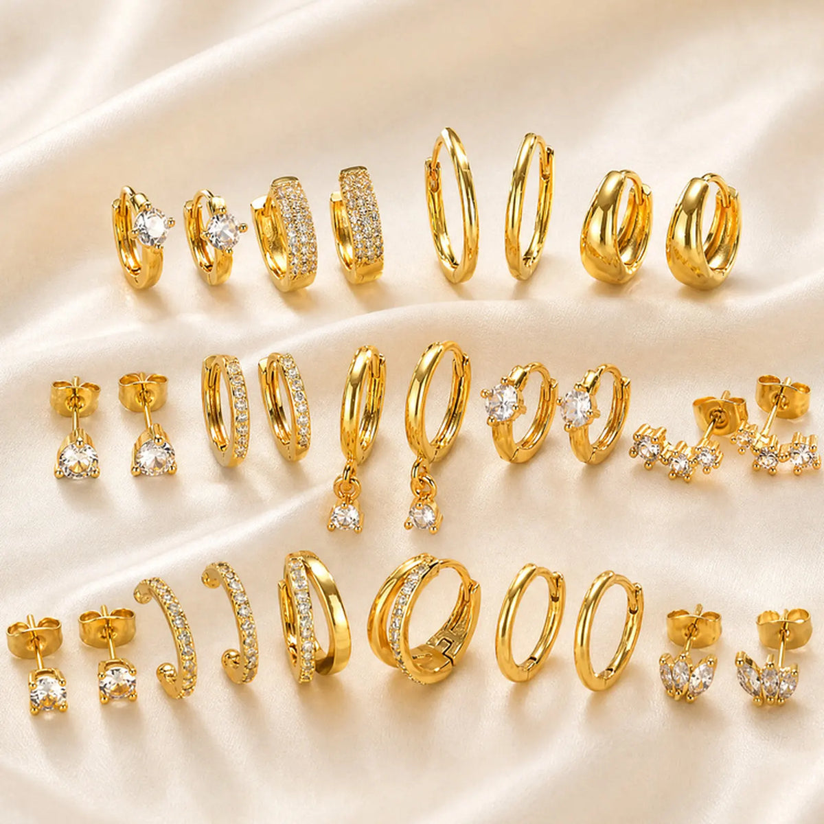 Gold-plated CZ earring set, multiple huggie hoops and small stud earrings laid out