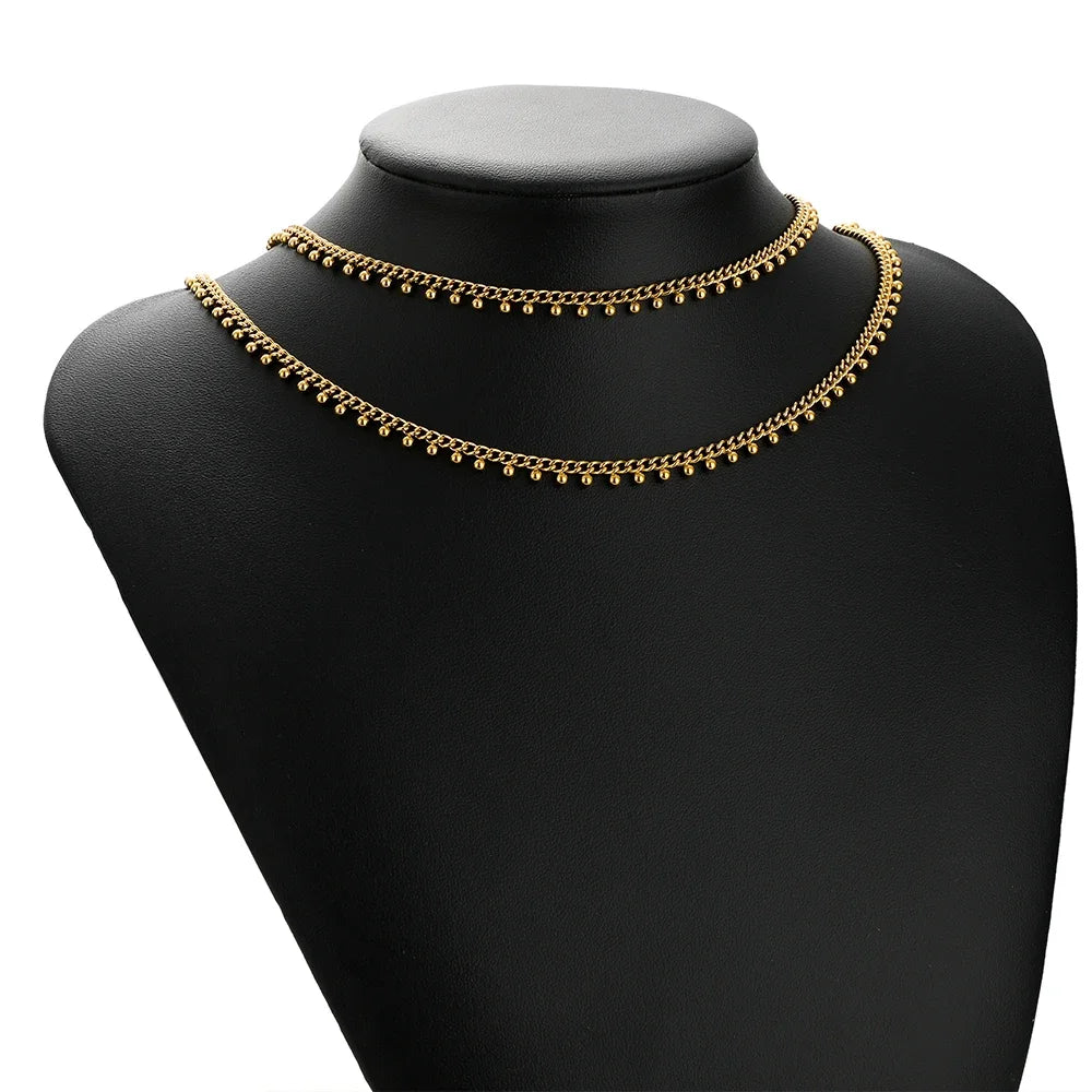 Gold beaded curb link chain layered necklace on a black mannequin bust