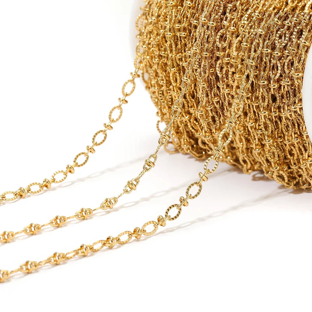 Close-up gold oval link chain strand draping from a white spool