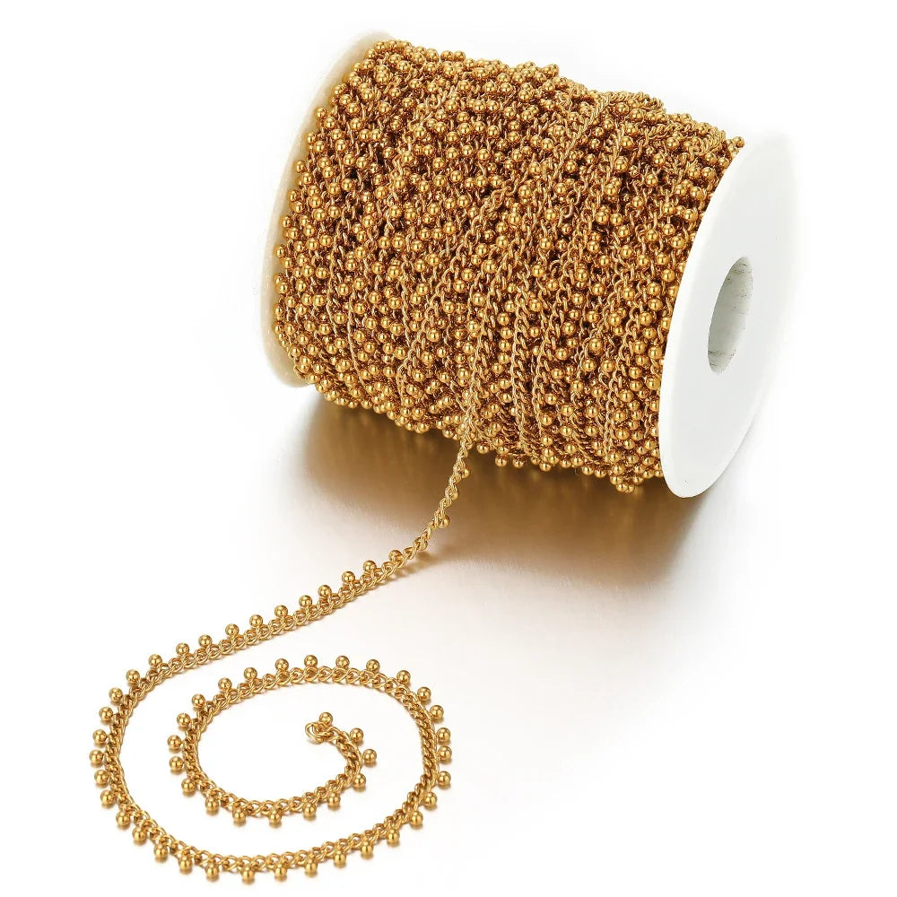 Gold beaded curb link chain on a spool, with small ball drop links