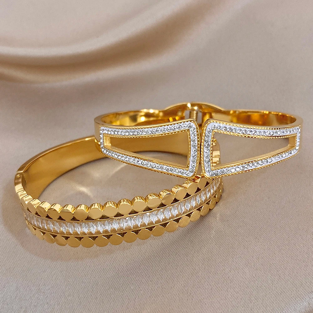 Gold-tone cuff bangles with geometric openwork panels and sparkling rhinestone accents