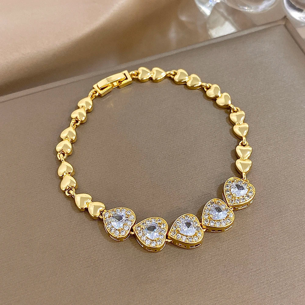 Gold-tone link bracelet with heart charms and round rhinestone stations