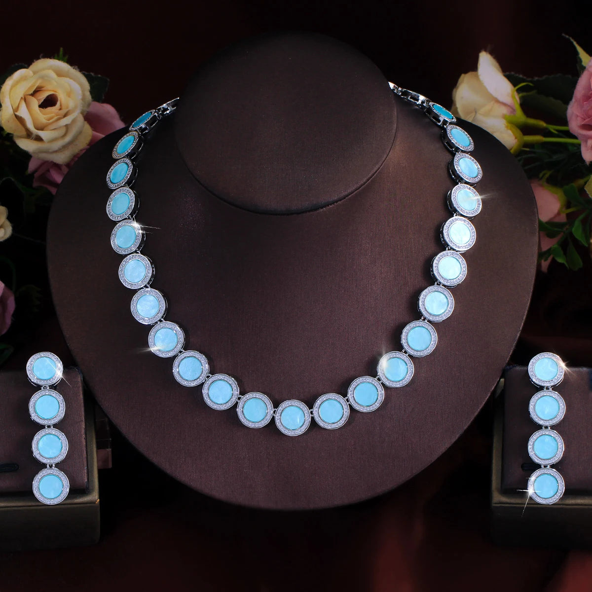 Light blue round halo necklace and matching drop earrings displayed on stands