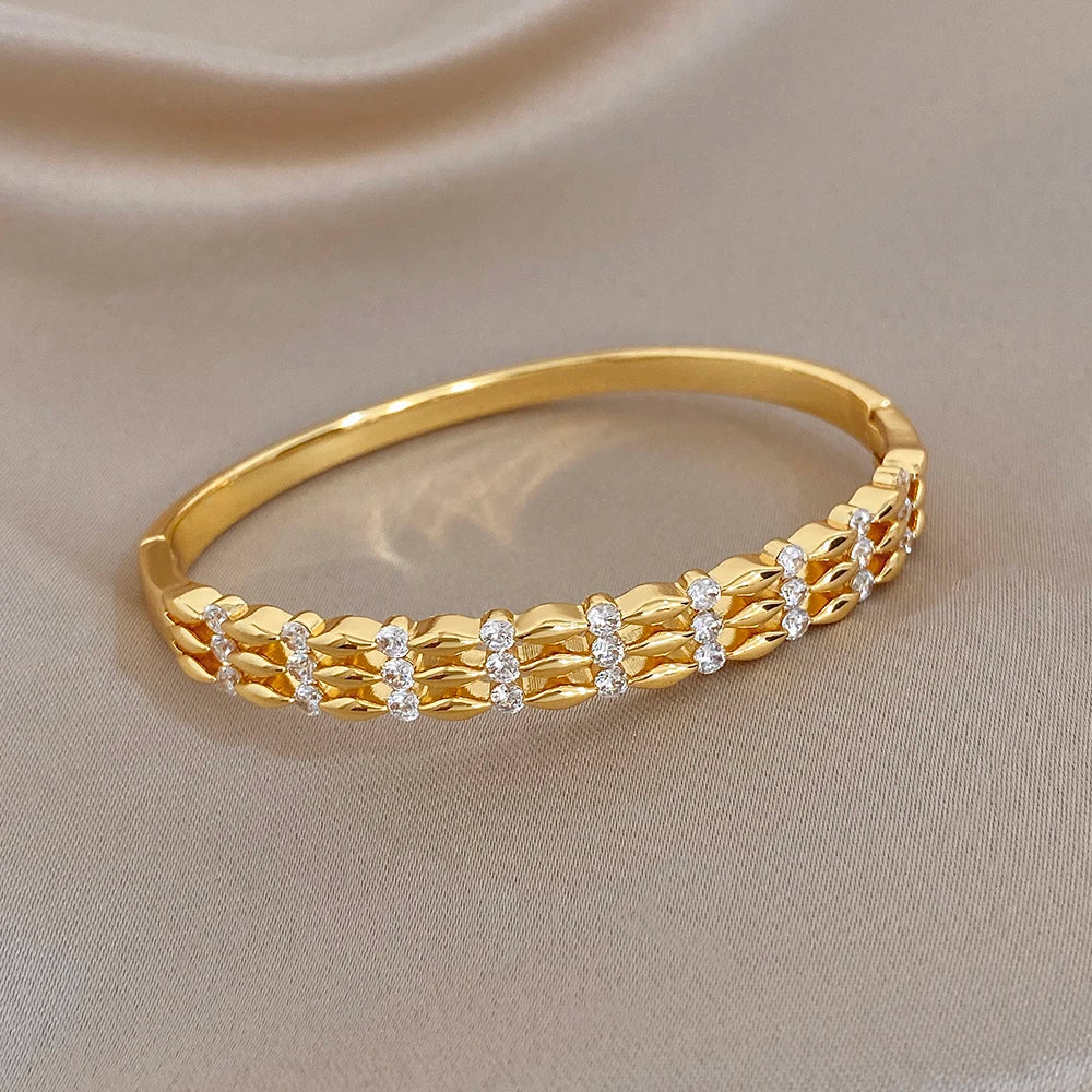 Gold-tone wide cuff bracelet with textured chain links and round crystal accents