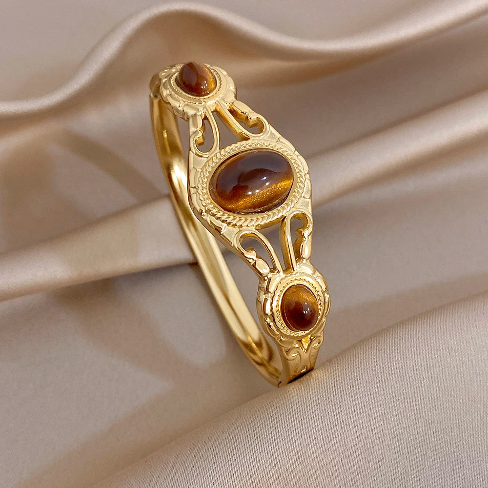 Gold-tone geometric cuff bangle with large oval brown tiger-eye center and accents