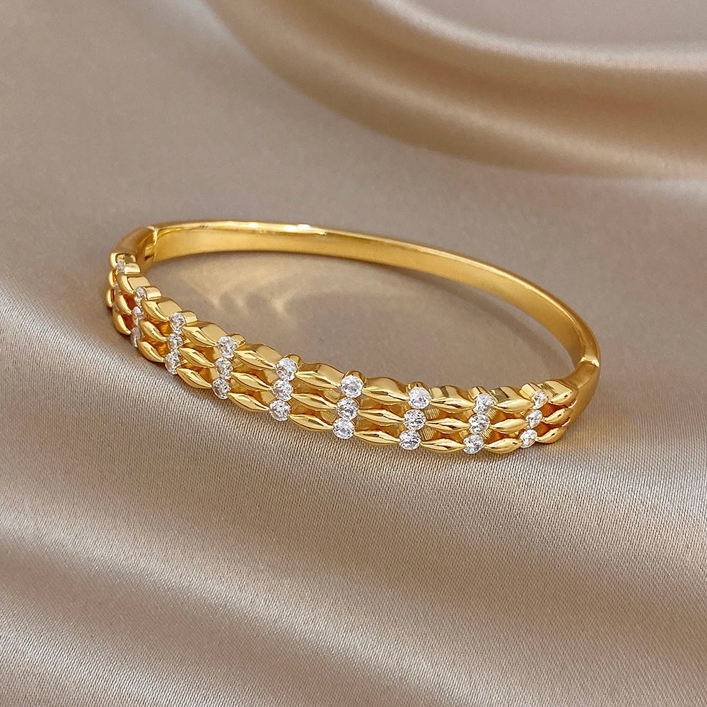 Wide gold cuff bangle with alternating textured links and small round sparkle stones