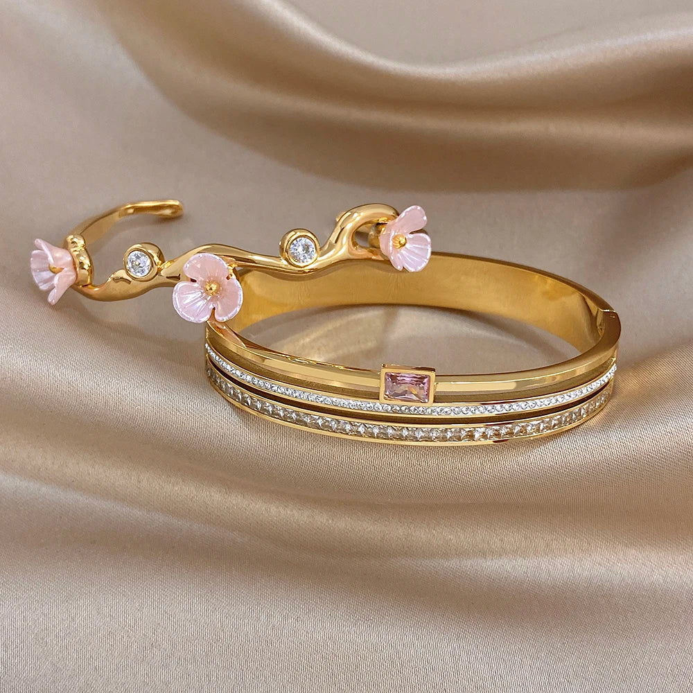 Gold-plated cuff bangle with pink flower charms and stacked rhinestone band