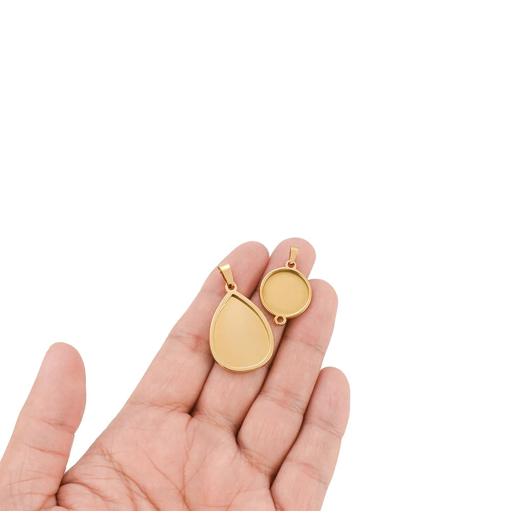 Round gold-tone cabochon pendant settings on keychain-style bails in hand