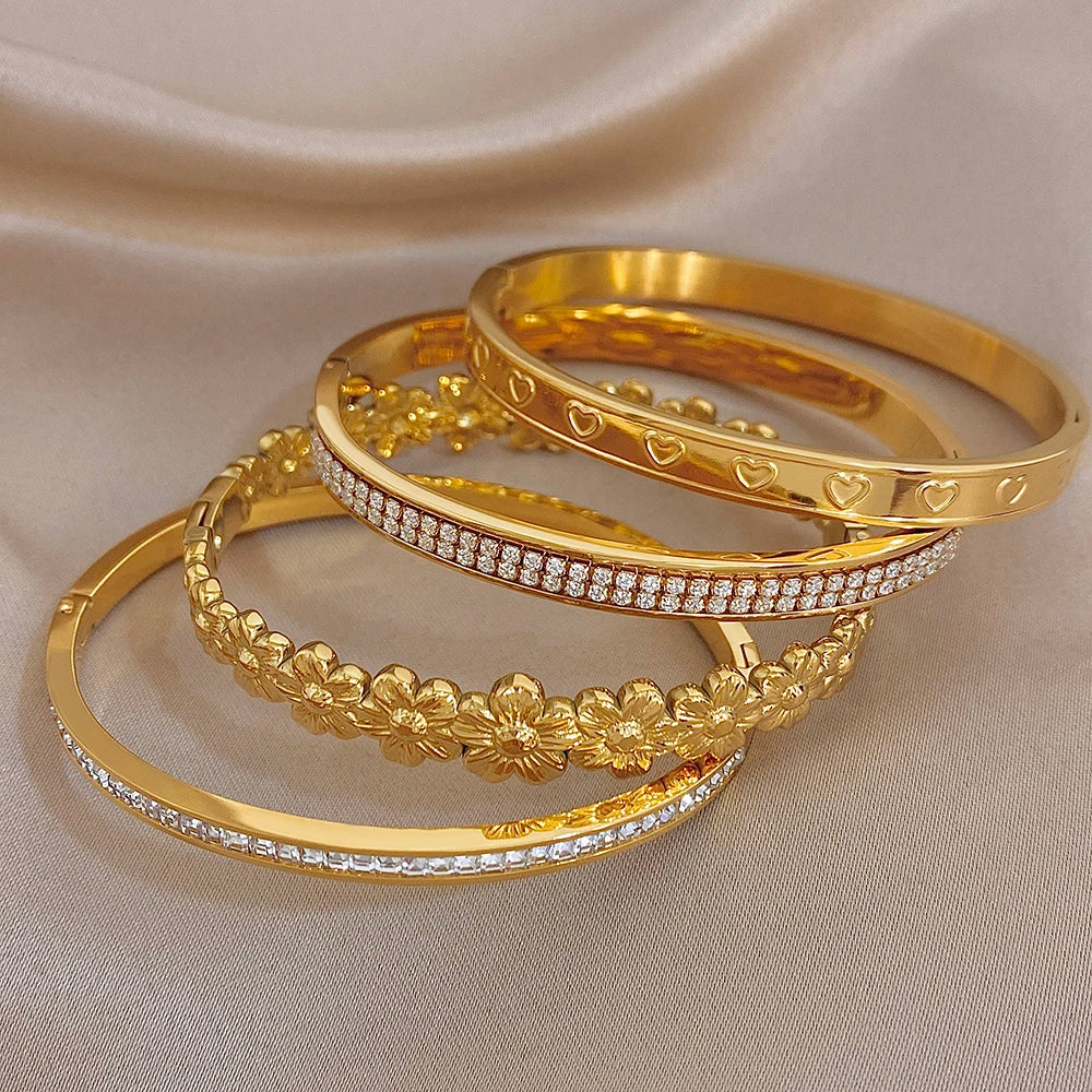 Gold tone cuff bangles with floral heart detailing and sparkling rhinestone border