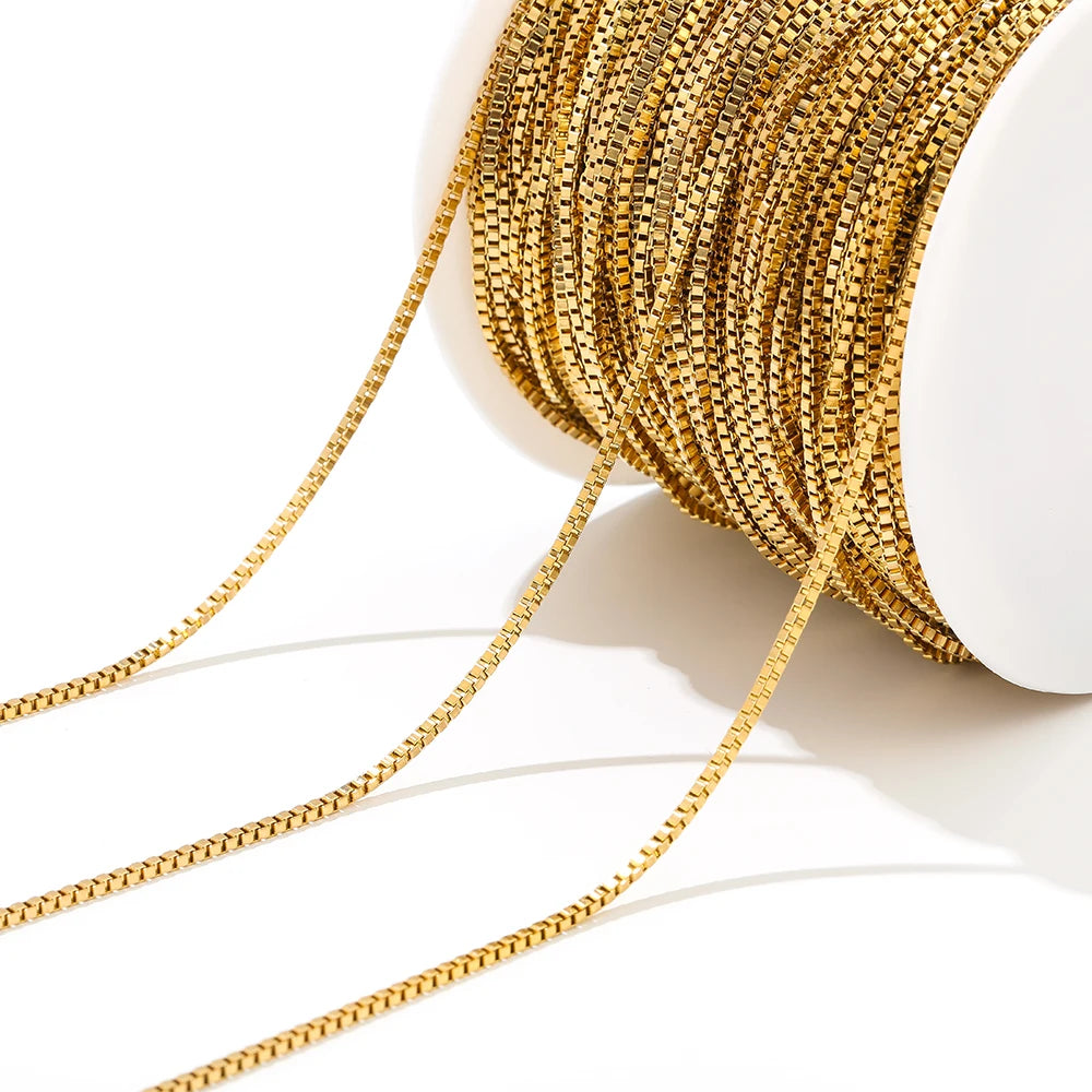 Gold box chain rolled on a white spool, close-up of interlocking links