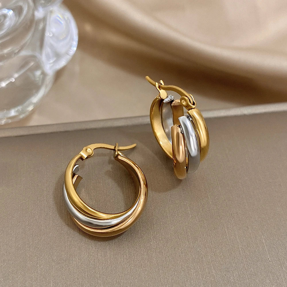 Two-tone twisted hoop earrings shown with their hinged clasps open