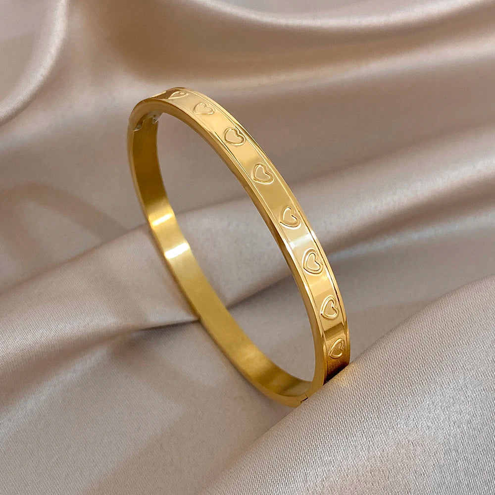 Single gold tone heart-carved bangle with polished sheen