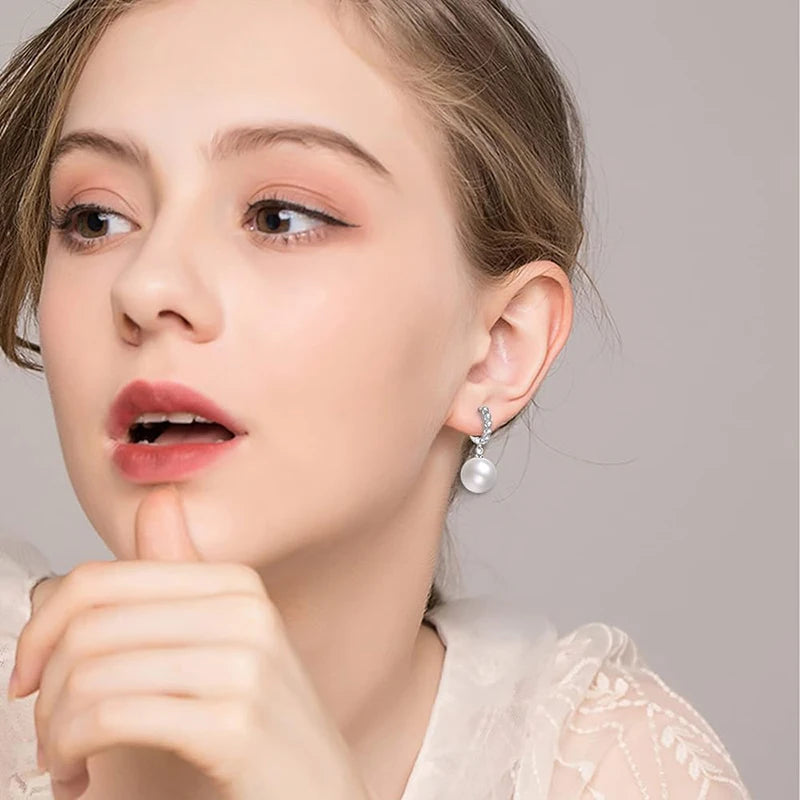 Zirconia and pearl drop earrings in silver-tone, worn on the ear
