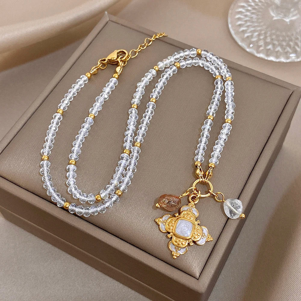 Gold-tone cross pendant necklace with clear crystal drops on triple-row silver beaded chain