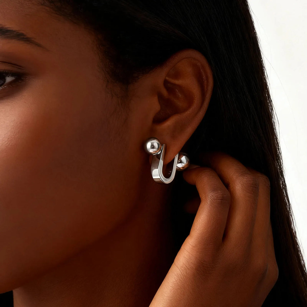 Silver U-shaped hoop earring with a round ball end, worn on the ear