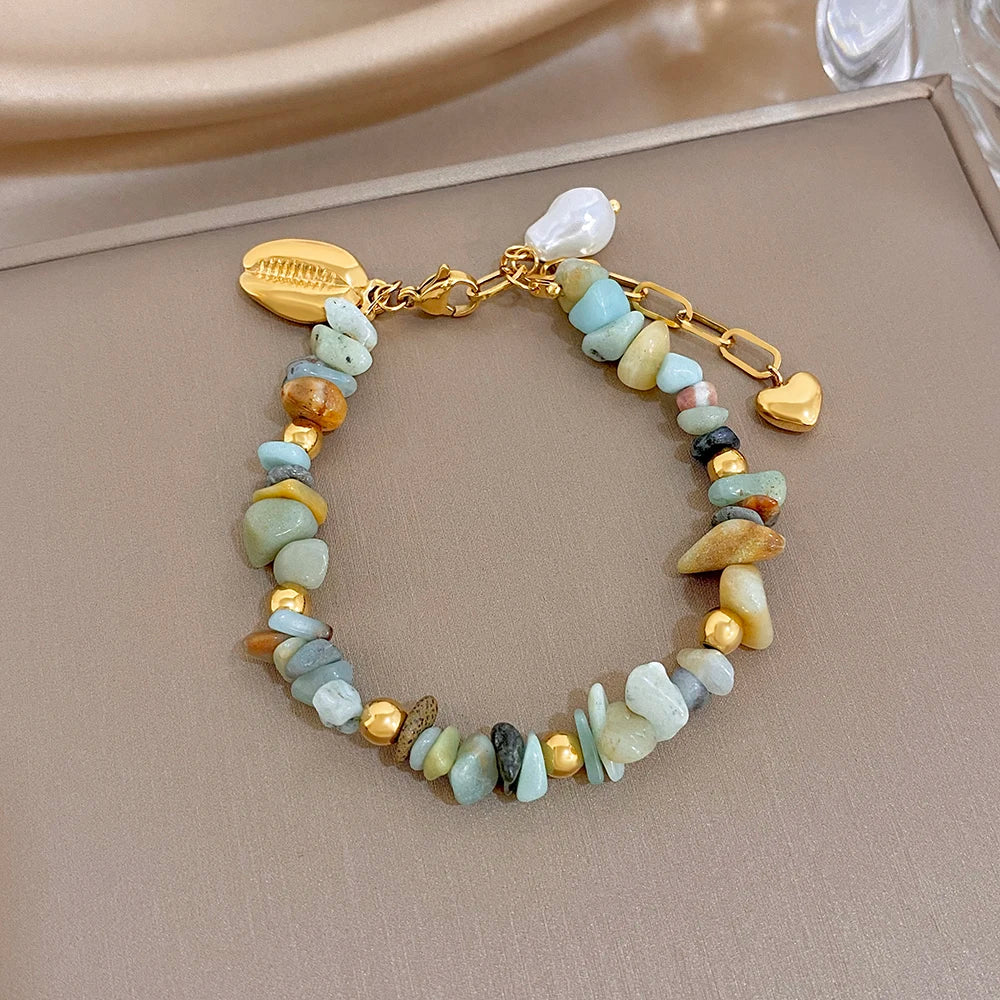 Gold link charm bracelet with irregular pale blue and cream stones, seashell pearl and heart dangle