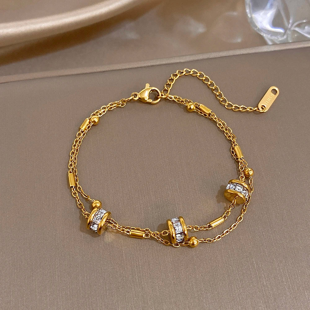 Gold double-layer chain bracelet with rhinestone bead cylinders and lobster clasp.
