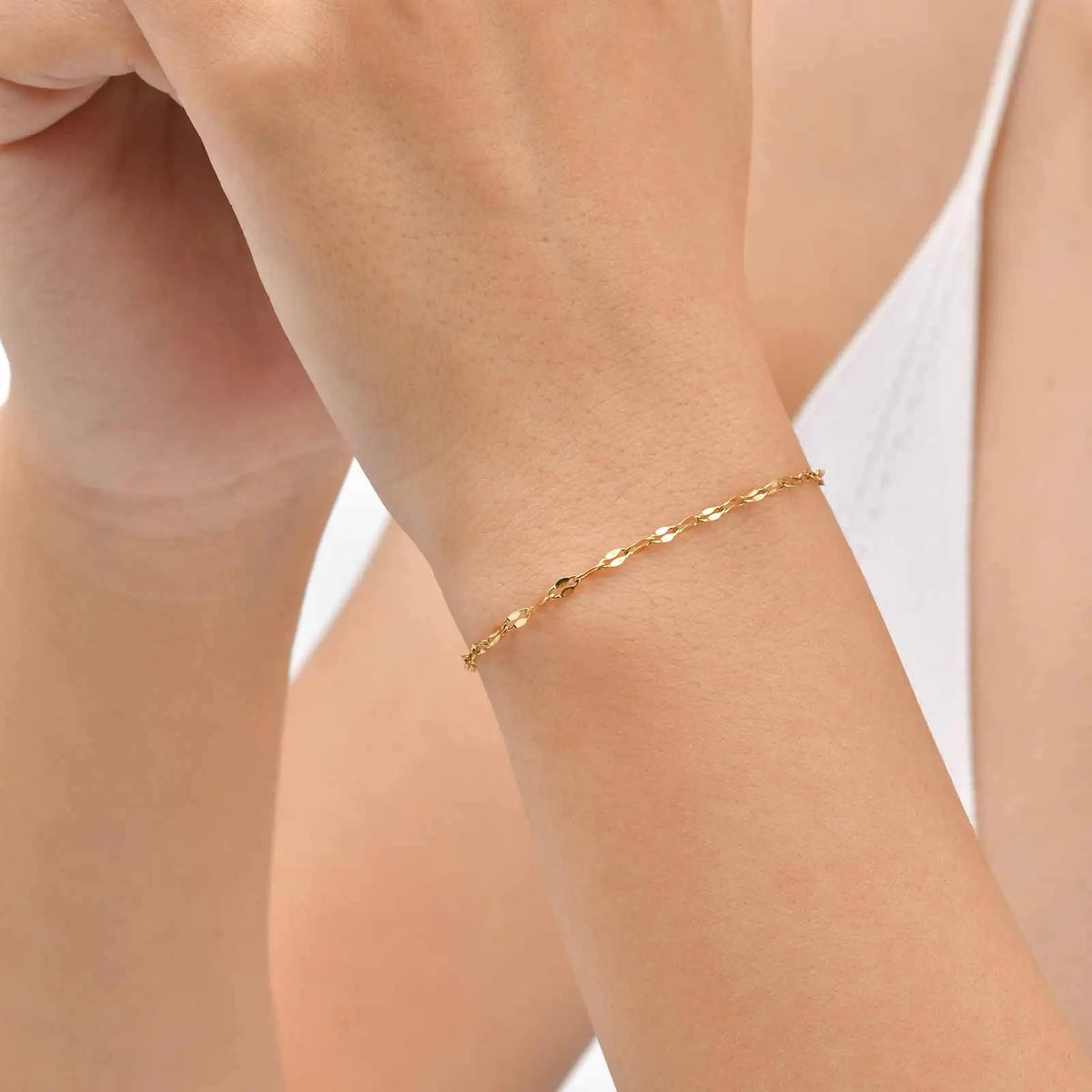 Gold tone thin chain bracelet worn on wrist with small linked pattern