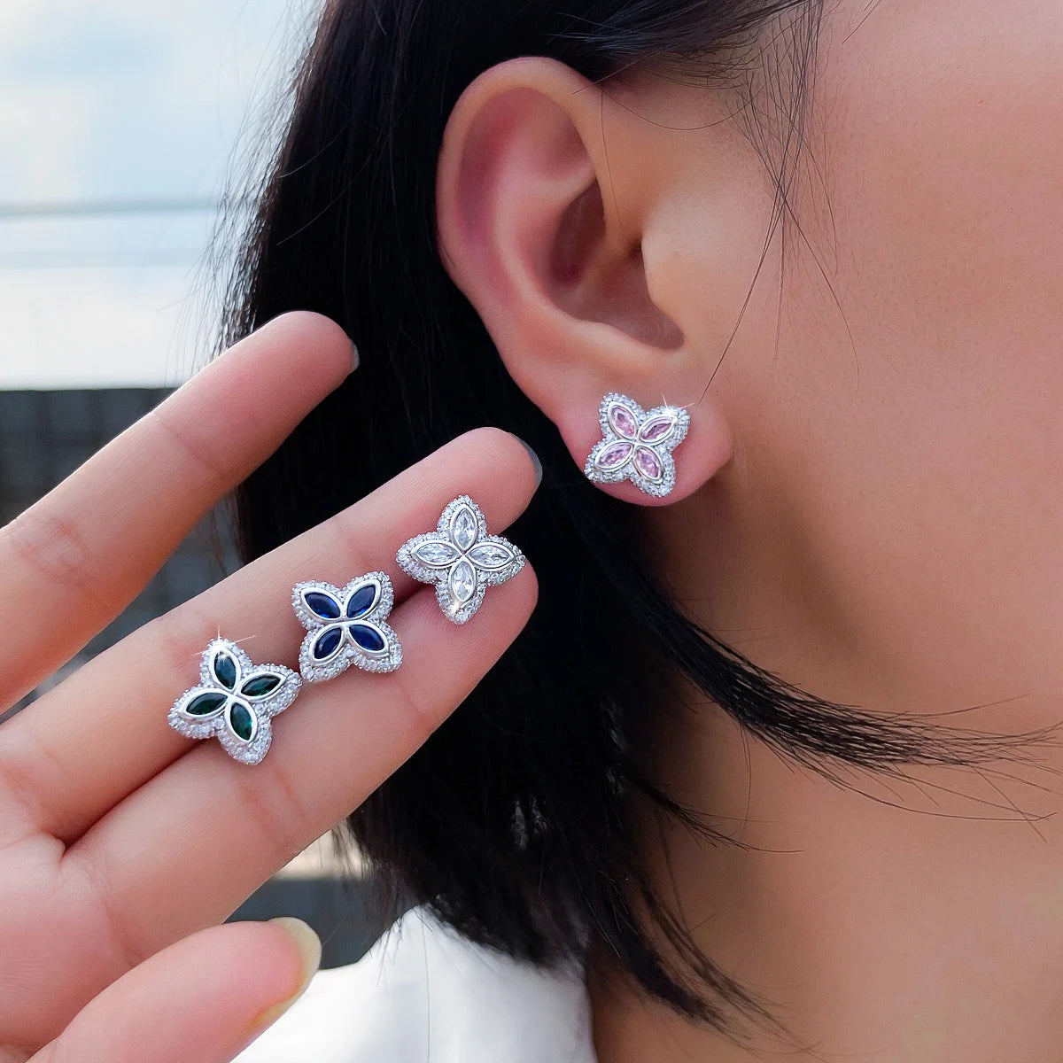 Four-leaf stud earrings in pink, blue, green and clear stones, shown worn and in hand