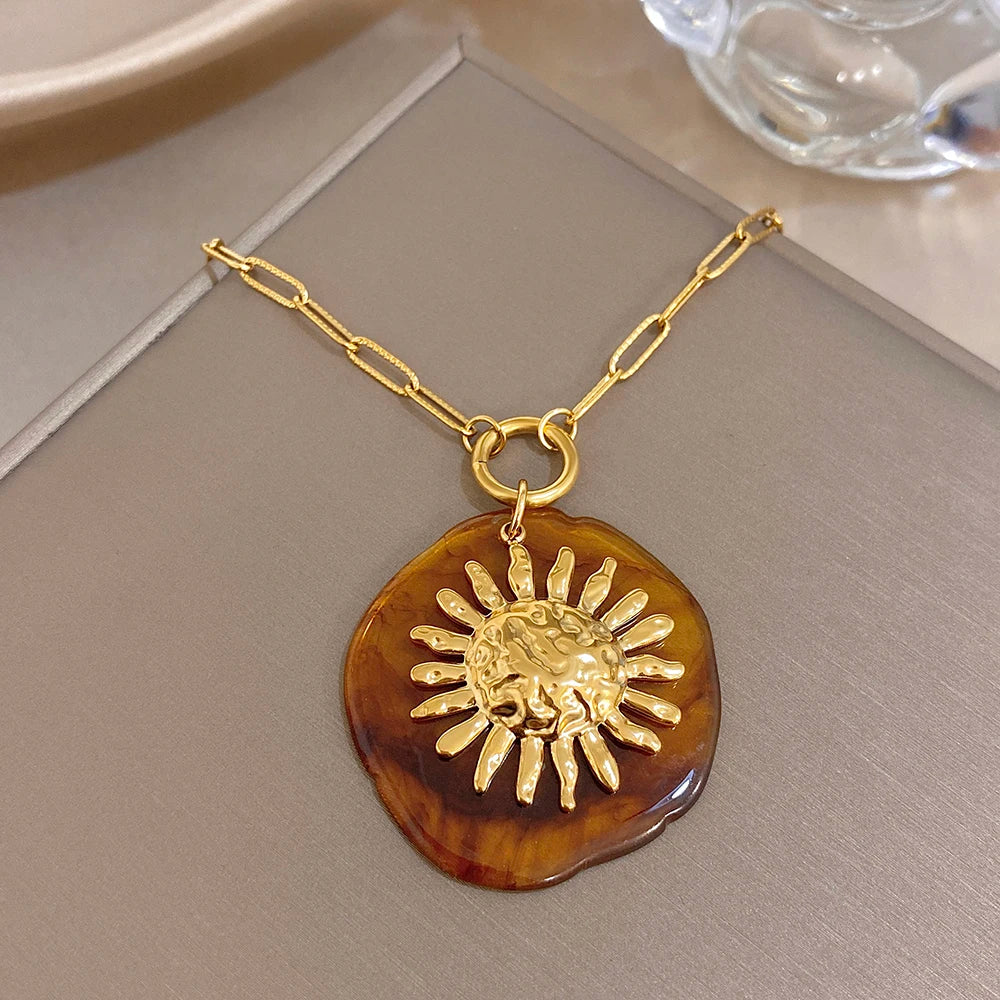 Gold-tone chain pendant necklace with amber round sun charm and raised sunburst design