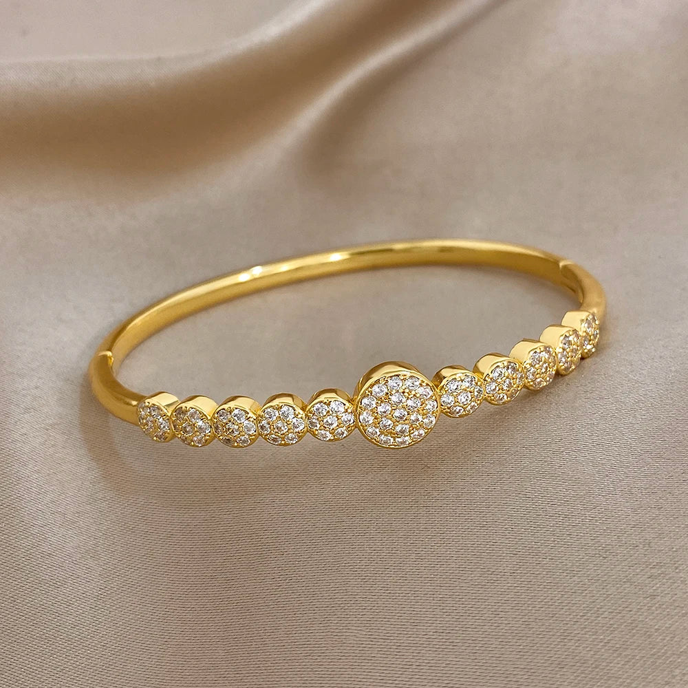 Gold-toned open cuff bangle with alternating round zircon stones across top